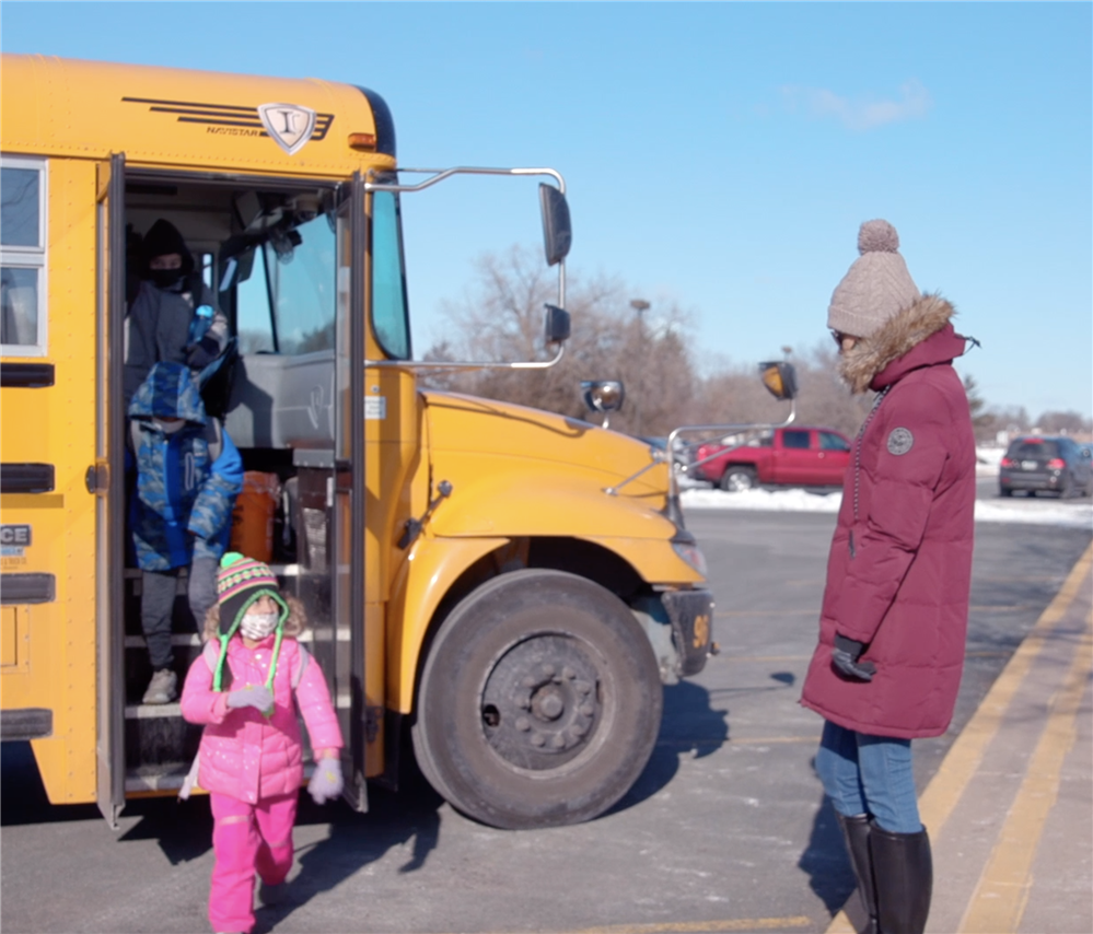  Teacher greets students unboarding bus